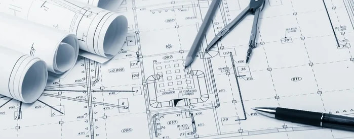 Rolled blueprints, a drafting compass, and a pen resting on a residential floor plan